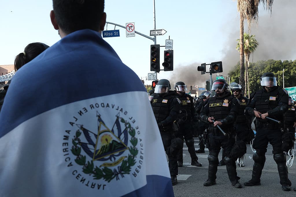 A lo lejos, manifestantes como este, que lleva consigo la bandera de El Salvador, se mantenían atentos a la situación, pero firmes en sus denuncias contra ICE.