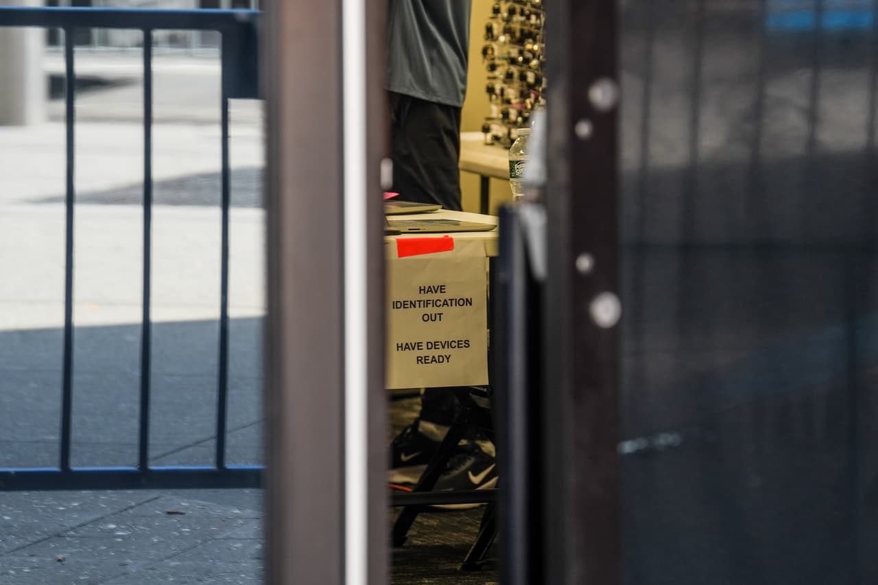 Adentro del puesto del control de entrada se observa una leyenda para todos los que entran al sitio: "Tenga su identificación fuera, tenga sus dispositivos listos".