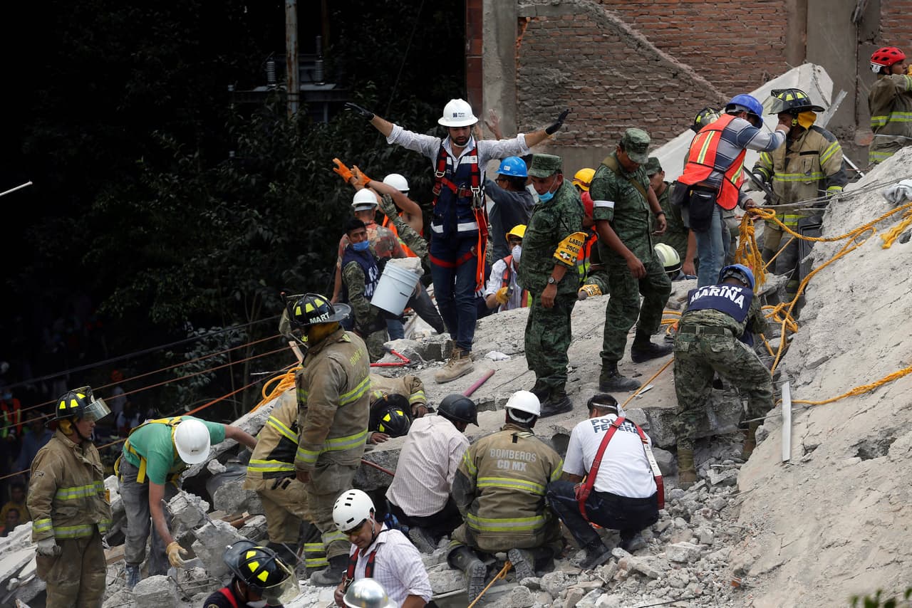 A rescue worker motions for everybody to be quiet as they are searching for people under the rubble of a collapsed building after an earthquake hit Mexico City, Mexico September 19, 2017. REUTERS/Claudia Daut