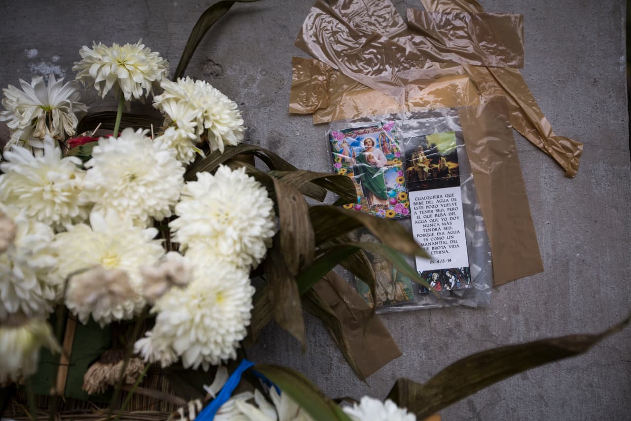 Estampas con oraciones se ven pegadas a un muro cerca de un altar en memoria de los fallecidos en una escuela.