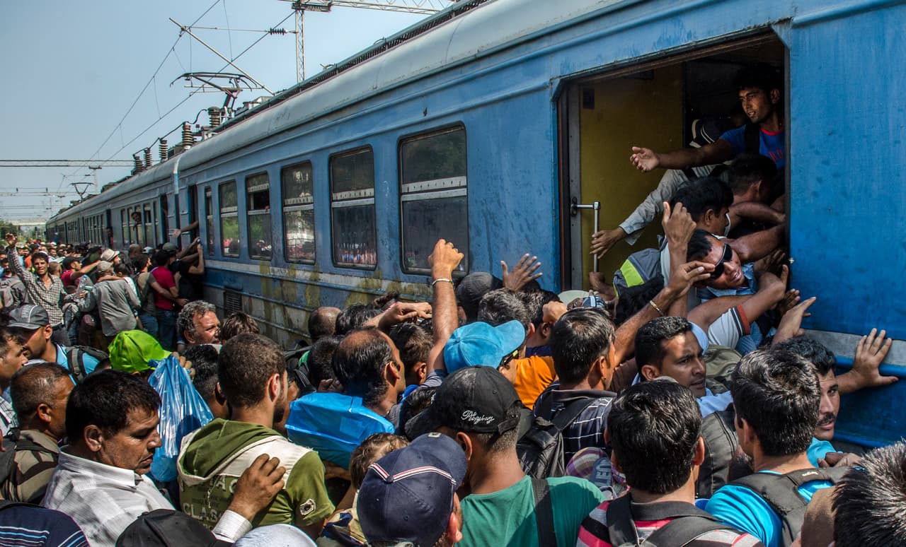 <b>Capítulo 3. “Somos personas, no somos animales”. </b>Un policía se lleva detenidos a los dos periodistas. No tienen el permiso escrito, diario, para hacer fotografías en la caótica estación. Tras casi una hora detenidos son puestos en libertad con la amenaza de peores consecuencias. Dos veces más serán detenidos en los siguientes días, afortunadamente sin graves problemas. Pasan las horas y el viejísimo tren de metal se convierte en un horno para las personas hacinadas en su interior. Las escasas botellas de agua se convierten en una necesidad absoluta para los niños, que casi no pueden ni respirar dentro de los vagones. Por las ventanillas abiertas se ven bebés asomados, sujetos por sus agobiados y sudorosos padres, cuyos ojos se iluminan cuando alguien les entrega un poco de agua desde el andén. Las escenas de la estación recuerdan a los vagones de ganado en el que los judíos eran llevados a los campos de exterminio.
<b><a href="http://huelladigital.univisionnoticias.com/crisis-refugiados-javier-bauluz/capitulo-3/">(VER ESPECIAL COMPLETO).</a></b>