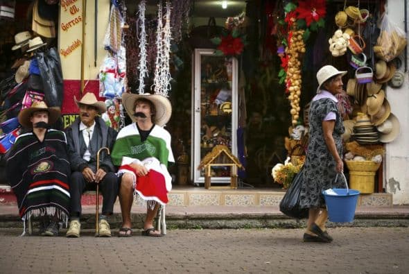 Joel Kowalski y Dane Jackson lucen atuendos tradicionales sentados junto a un lugareño durante el Primer Descenso Red Bull: Proyecto Michoacán, en Uruapan, MI, México, 24 de Noviembre, 2013.
