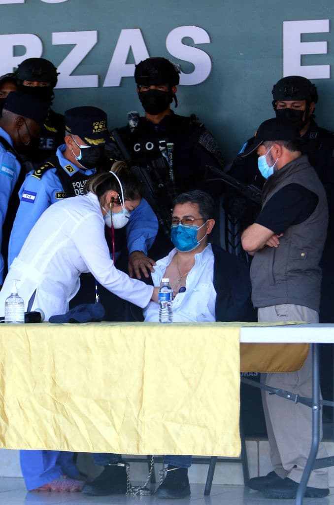 Un médico revisa al expresidente hondureño Juan Orlando Hernández, que permanece esposado en la sede de la Policía de Honduras tras recibir una orden de extradición de Estados Unidos en Tegucigalpa, el 15 de febrero de 2022.