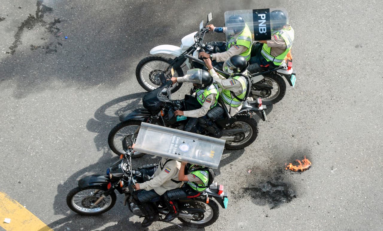 Miembros de la Policía Nacional se protegen de los objetos contundentes lanzados por los manifestantes desde el segundo piso de la autopista.