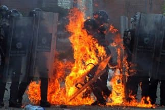 Un policía envuelto en llamas a causa de una bomba molotov en San Cristóbal, durante protestas contra el programa de toma de huellas digitales impulsado por el gobierno de Maduro.