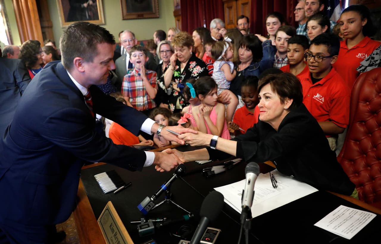 "Entiendo y anticipo que esto probablemente será impugnado en los tribunales, y que los tribunales incluso pueden suspender la ley hasta que llegue a la Corte Suprema", dijo Reynolds durante la firma de la ley de este viernes,
<b> rodeada de niños de distintas edades</b>. En la imagen, saluda al líder de la mayoría en el Senado de Iowa, Jack Whitver, después de firmar la legislación.