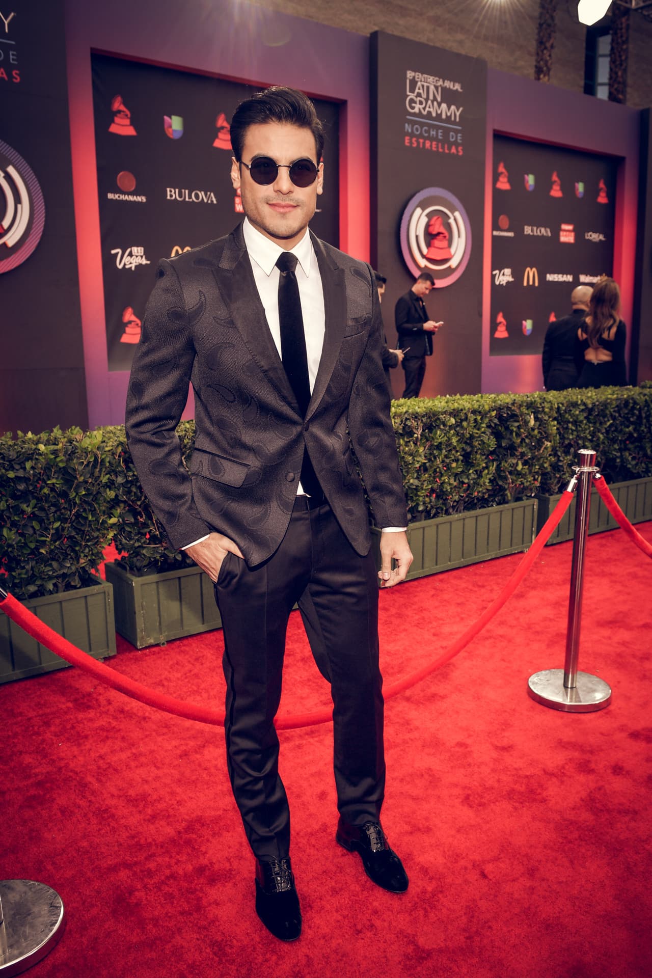 El cantante mexicano Carlos Rivera llegó a la alfombra del Latin GRAMMY en traje negro con estampado, corbata negra y lentes oscuros.