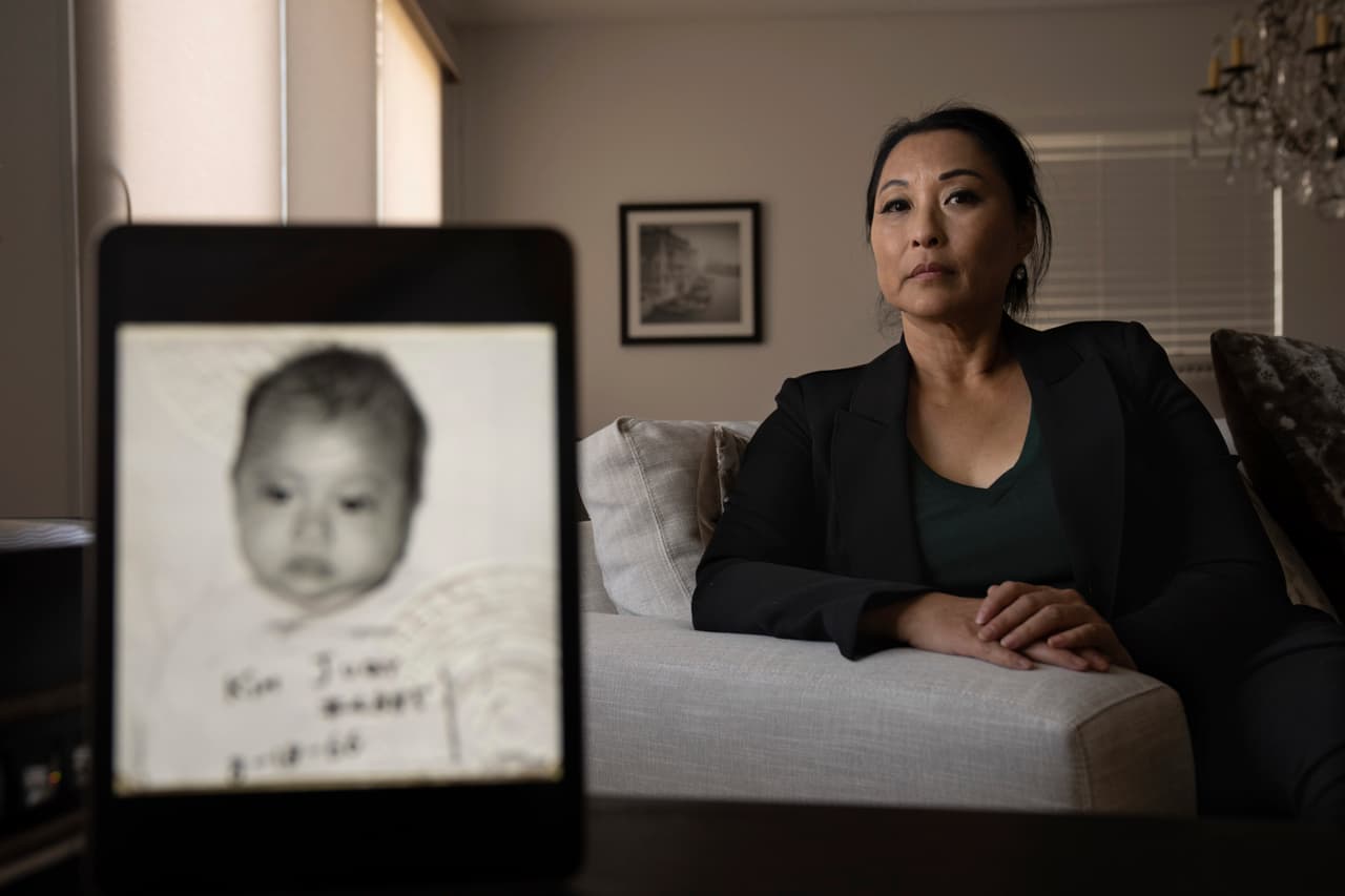 Joy Alessi posa para un retrato detrás de su foto de bebé, antes de que una familia en Estados Unidos la adoptara en Corea del Sur, el martes 25 de junio de 2024, en Henderson, Nevada.