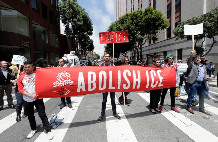 Los manifestantes sostienen carteles delante de la oficina del Servicio de Inmigración y Control de Aduanas (ICE).