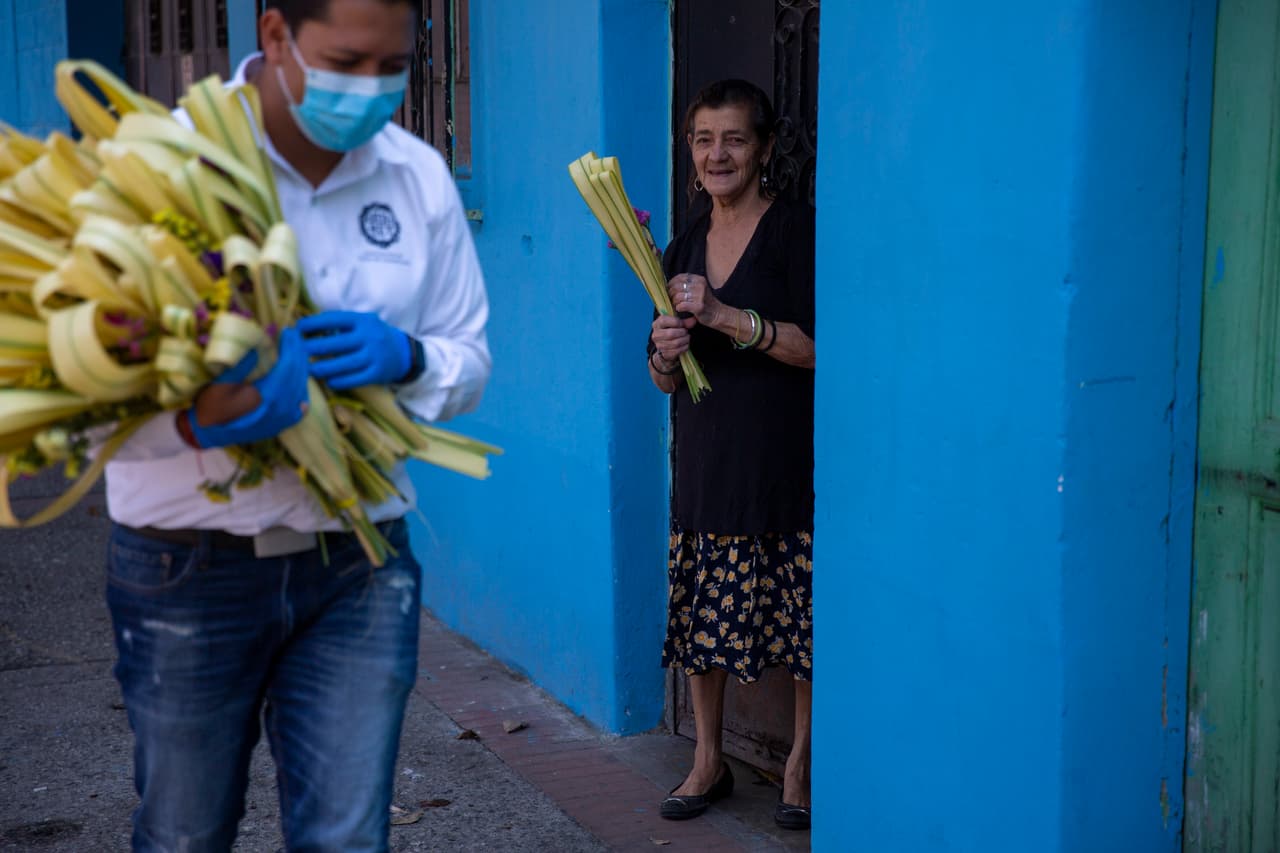 <b>Devoción a pesar de la crisis.</b> Una mujer sonríe tras recibir una rama de palma el ‘Domingo de Ramos’, una tradición católica que coincidió con la pandemia. Ciudad de Guatemala, 5 de abril.