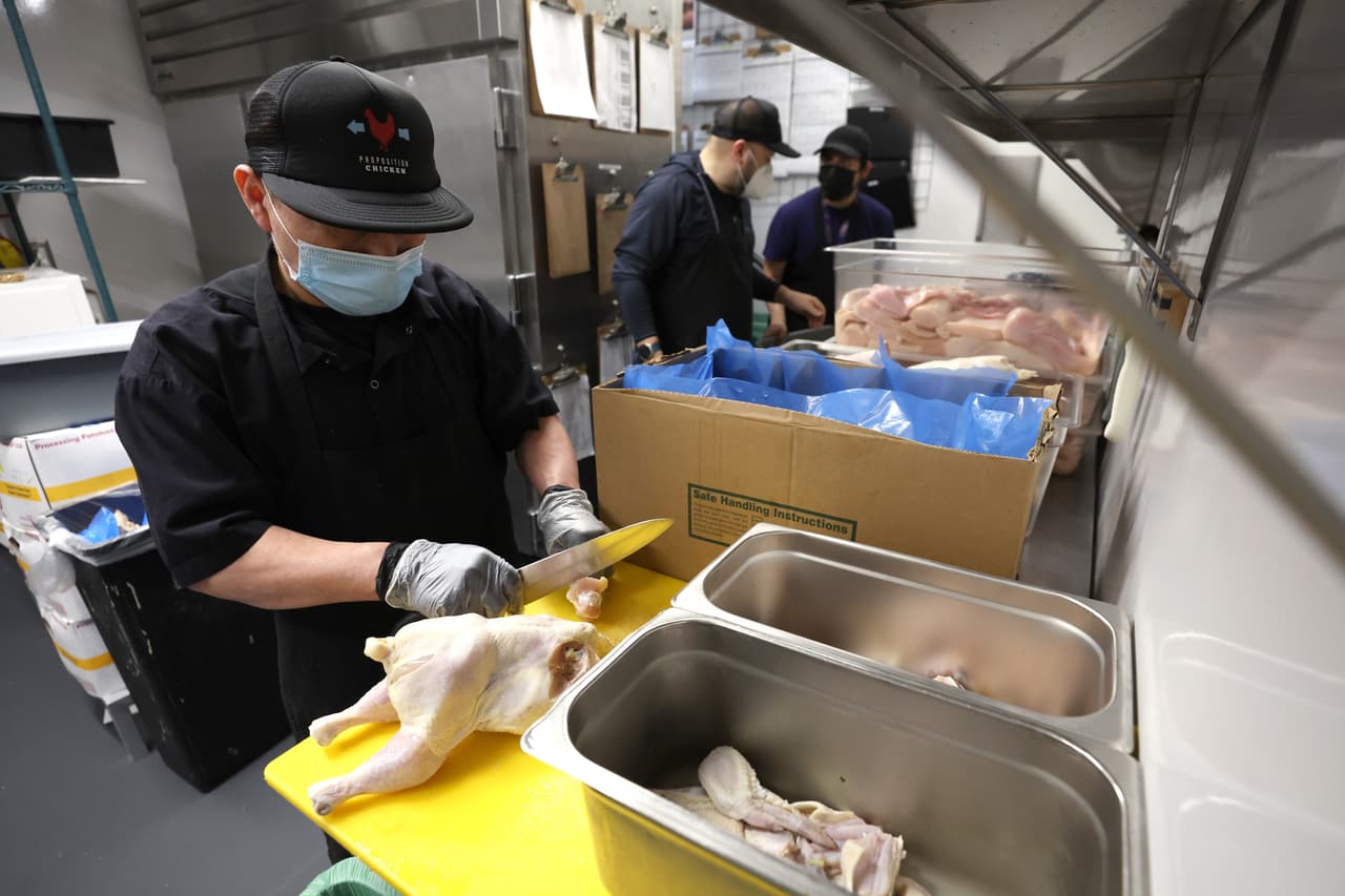 Un cocinero de Proposition Chicken desprende las alas de un pollo como parte de su trabajo.
