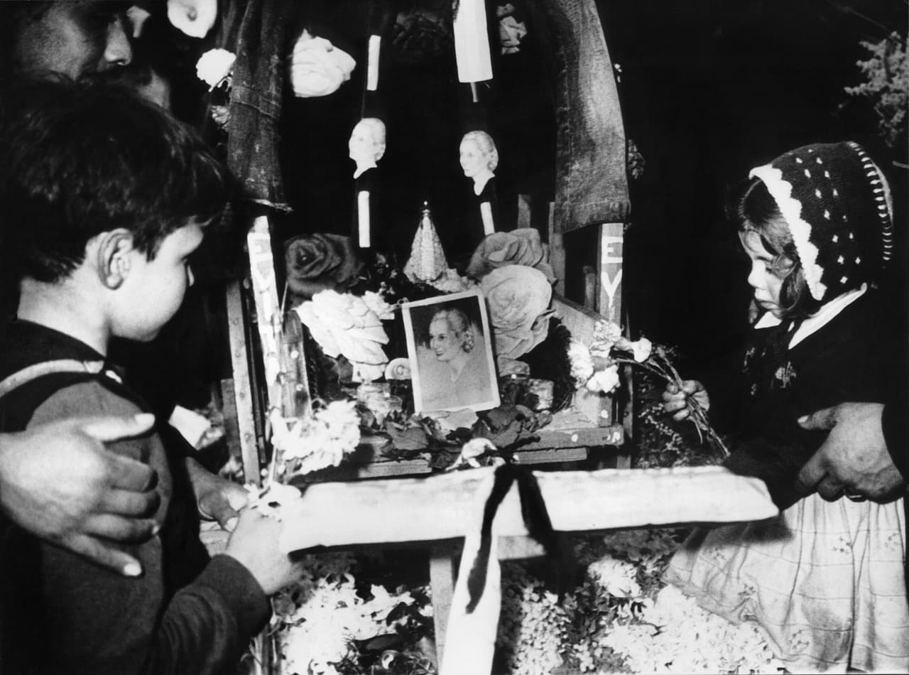 Tras un masivo funeral, el cuerpo de Eva fue a 'descansar' a la sede de la Central General de Trabajadores (CGT). La 
<b>historia que siguió después con su cadáver, es digna de un cuento de terror. </b>
<br>
<br>En la imagen, algunas personas dejan ofrendas de flores en el funeral de Eva Perón. 
<br>