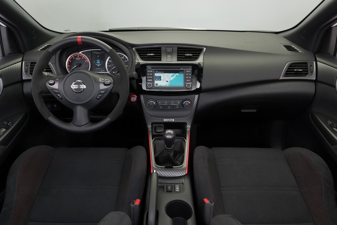 El interior del Nissan Sentra NISMO presenta aspectos deportivos, como su 
<b>volante</b>, revestido en 
<b>cuero y alcántara</b>, con claras reminiscencias de la competición. Además, continúan las líneas en rojo, detalles propios de la gama deportiva de la marca.