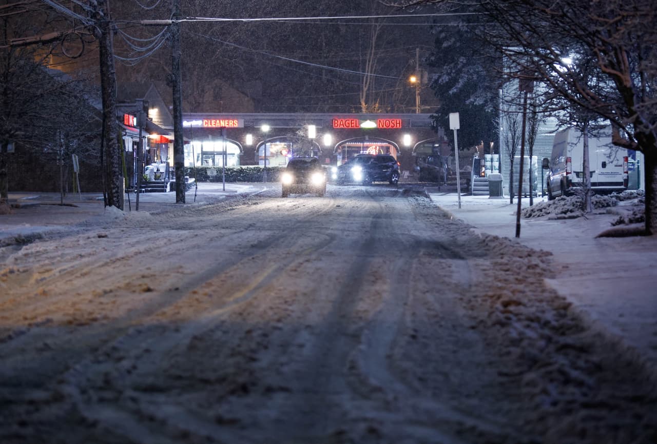 En Nueva Jersey también se reportó la acumulación de nieve en algunas zonas. Esta imagen muestra automóviles circulando por una calle mientras la nieve cae en Closter, Nueva Jersey, este 6 de enero. 
<br>