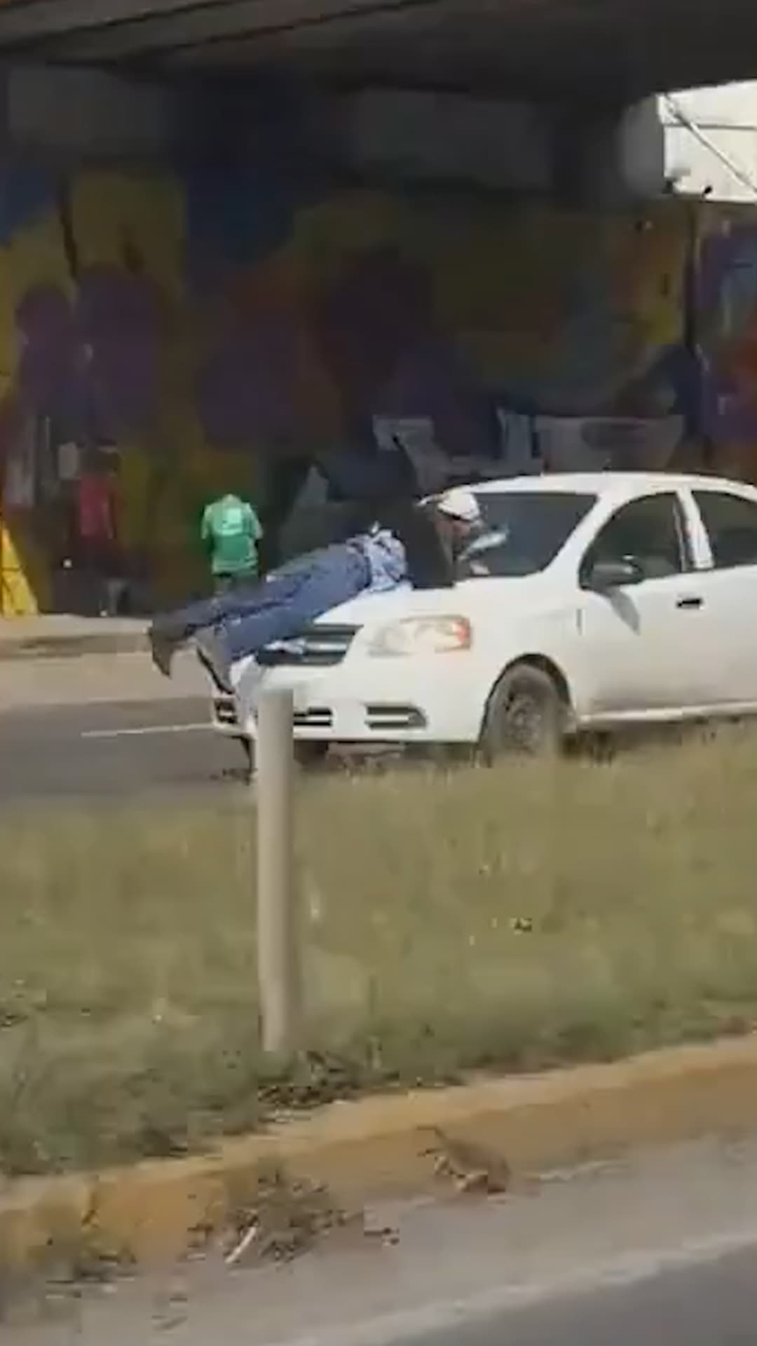 Se aferra al cofre de un auto