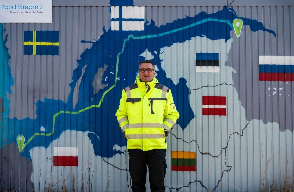 El alcalde de la ciudad costera alemana de Lubmin, en el noreste de Alemania, Axel Vogt, posa delante de un punto de información decorado con un mapa que muestra el gasoducto Nord Stream 2, que se esperaba que suministrara gas ruso a los hogares europeos, en el parque industrial de Lubmin, el 1 de marzo de 2022.