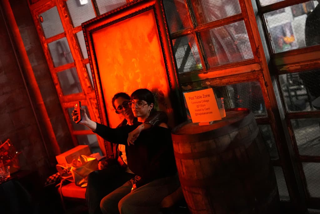 Gabriela Osuna, a la derecha, inmigrante venezolana con estatus de protección temporal, o TPS, que cofundó un exitoso colectivo de artistas que produce eventos artísticos, se toma una foto con su novia, Vanessa Sanchez Montero, de 29 años, también de Venezuela, en un bar en Doral, Florida, el sábado 5 de abril de 2025. (AP Foto/Rebecca Blackwell)