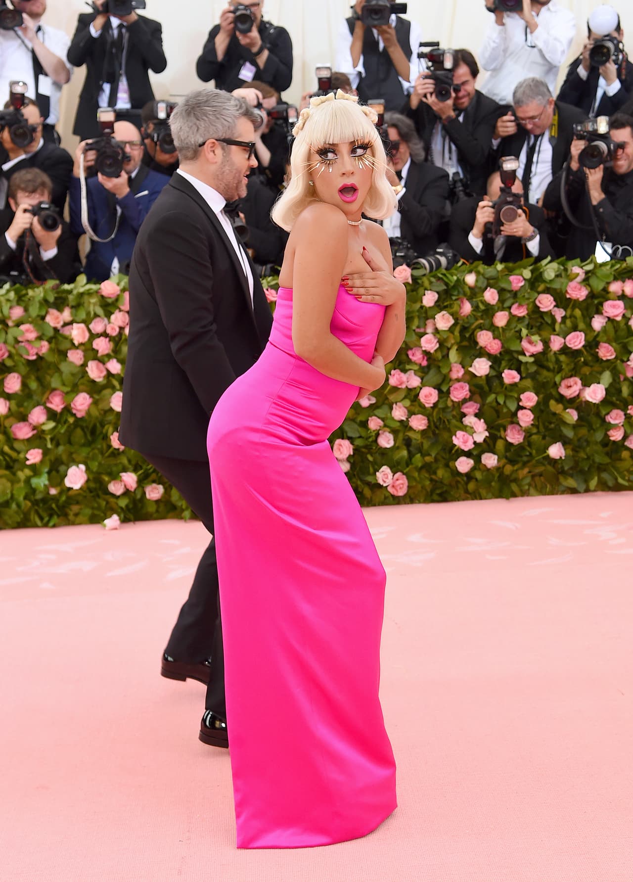 Debajo al vestido negro, la cantante llevaba otro vestido strapless en rosa encendido de corte columna.