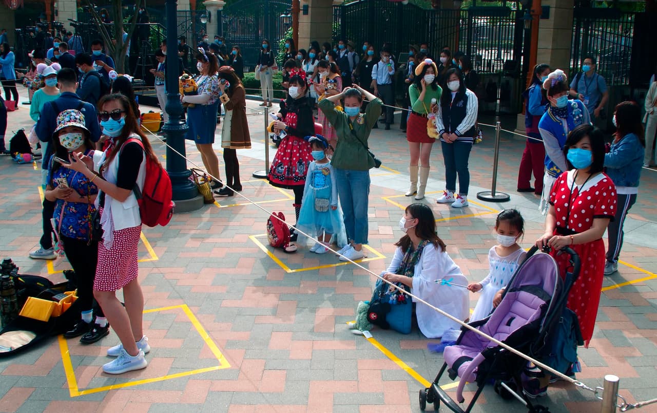 Los visitantes de Disneyland en Shanghai, China, esperan en los espacios dispuestos para mantener la separación. El parque, que reabrió el 11 de mayo, anunció que había establecido líneas divisorias para las filas de las atracciones, además de otras precauciones.