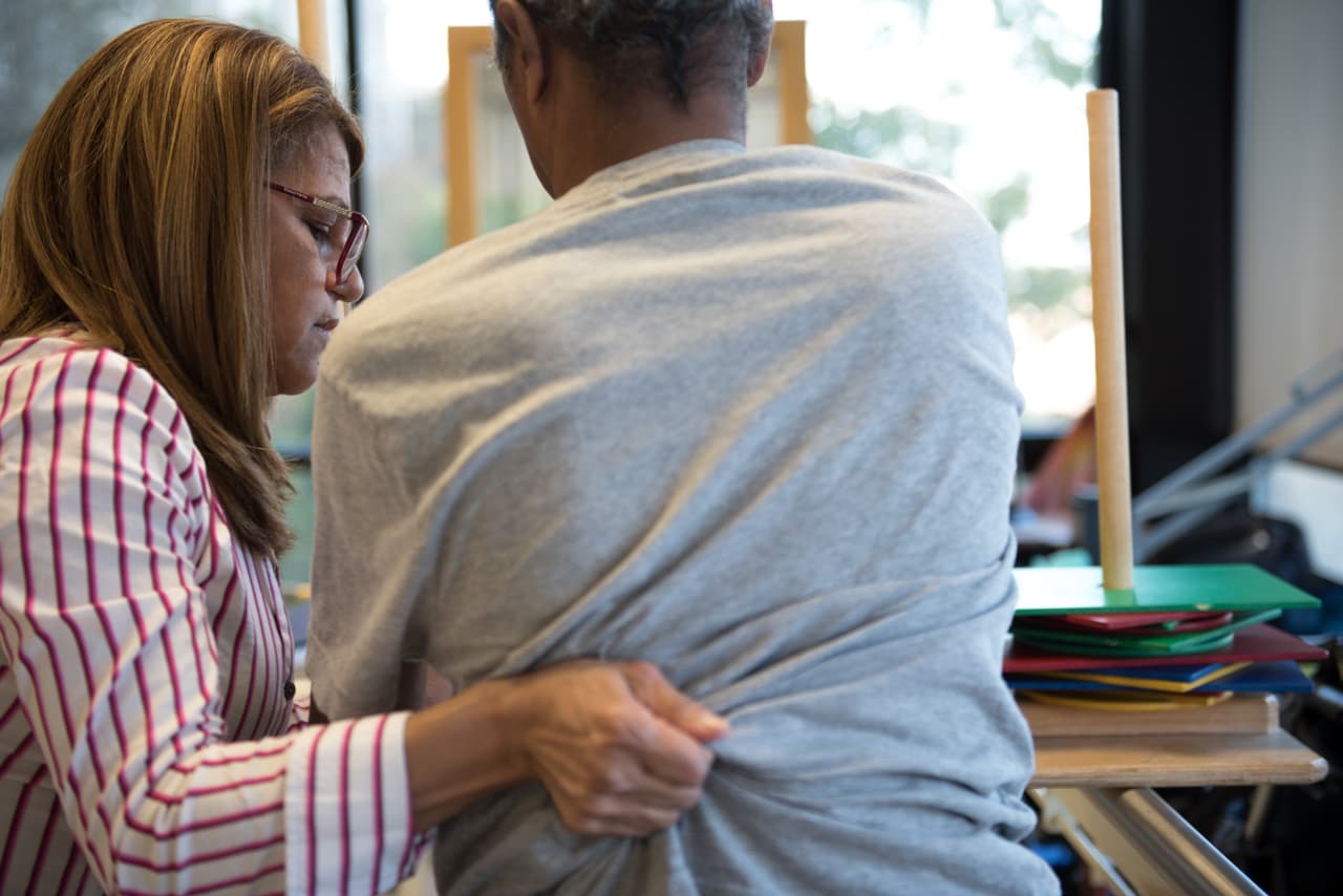 Luz Sanchez helps Gouroa Gomez back into his wheelchair. Luz Sanchez demonstrates the rehabilitation techniques she uses in her job at Fort Tryon Center for Rehab & Nursing in New York City, NY, on Novemeber 14, 2017. Gouroa Gomez, who suffered from a stroke six months ago and spent two months in hospital before coming to the Fort Tyron Center, is one of Luz's patients. Photo ©Skyler Reid for Univision Digital