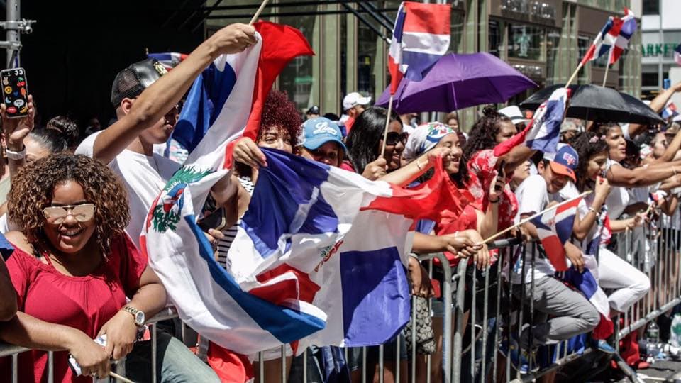 En esta foto de 2017 los dominicanos están sonriendo y agitando con orgullo su bandera.