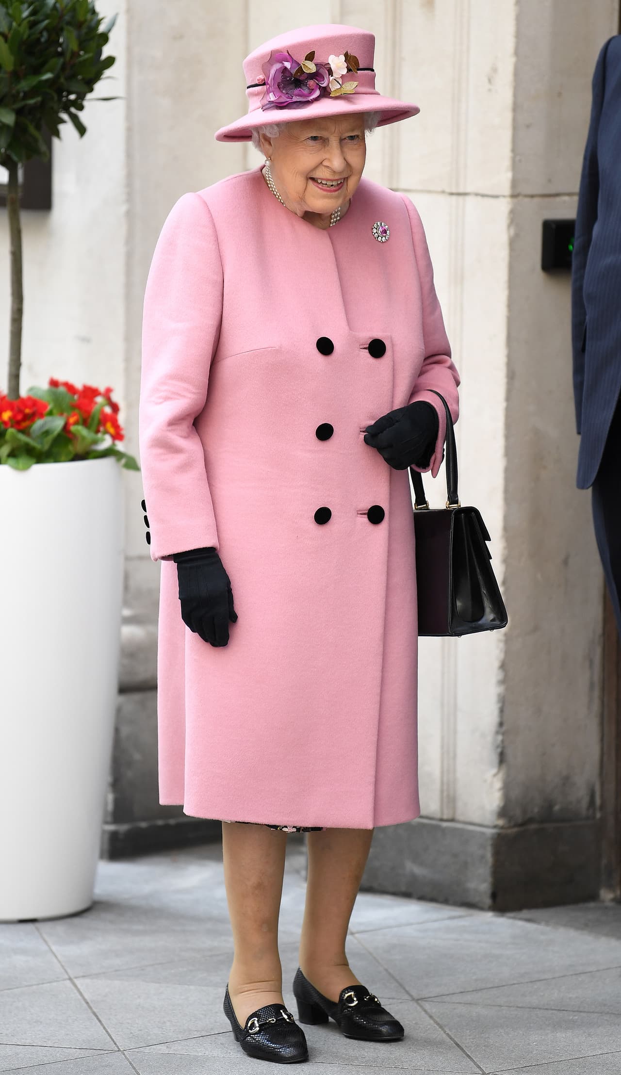 Por su parte, la reina Isabel II optó por un colorido abrigo rosa de Stewart Parvin que hacía juego con su sombrero y tenía un tocado de flores.