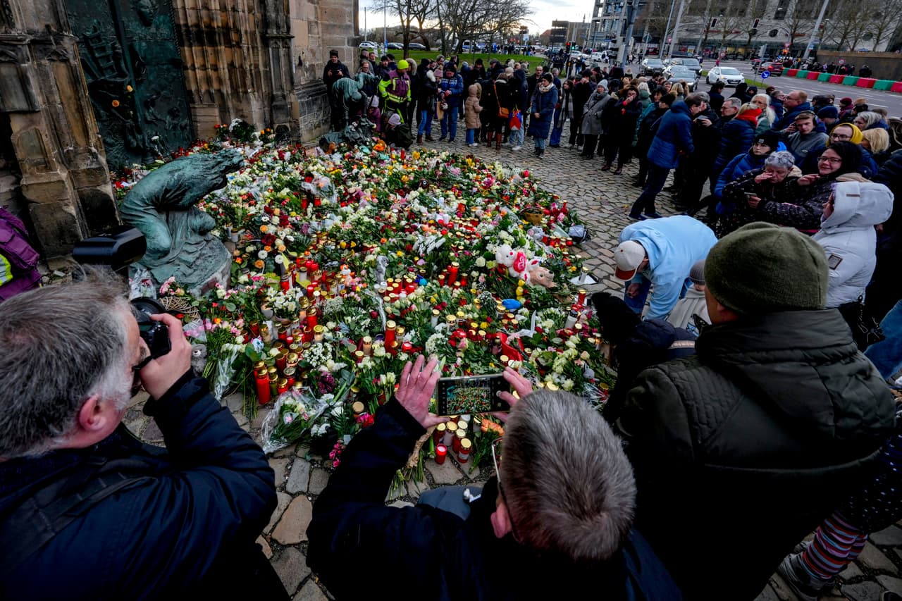 La gente coloca flores en la entrada de una iglesia cerca del mercado navideño de Magdeburgo, Alemania, el sábado 21 de diciembre de 2024.