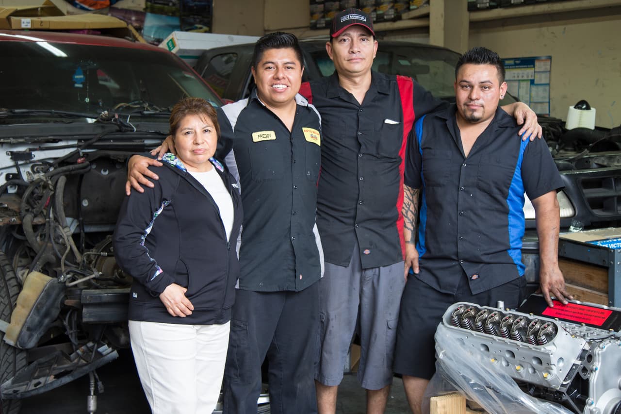 Freddy Avan acompañado de su madre Tommy Salinas y de dos de sus empleados en su taller de mecánica.