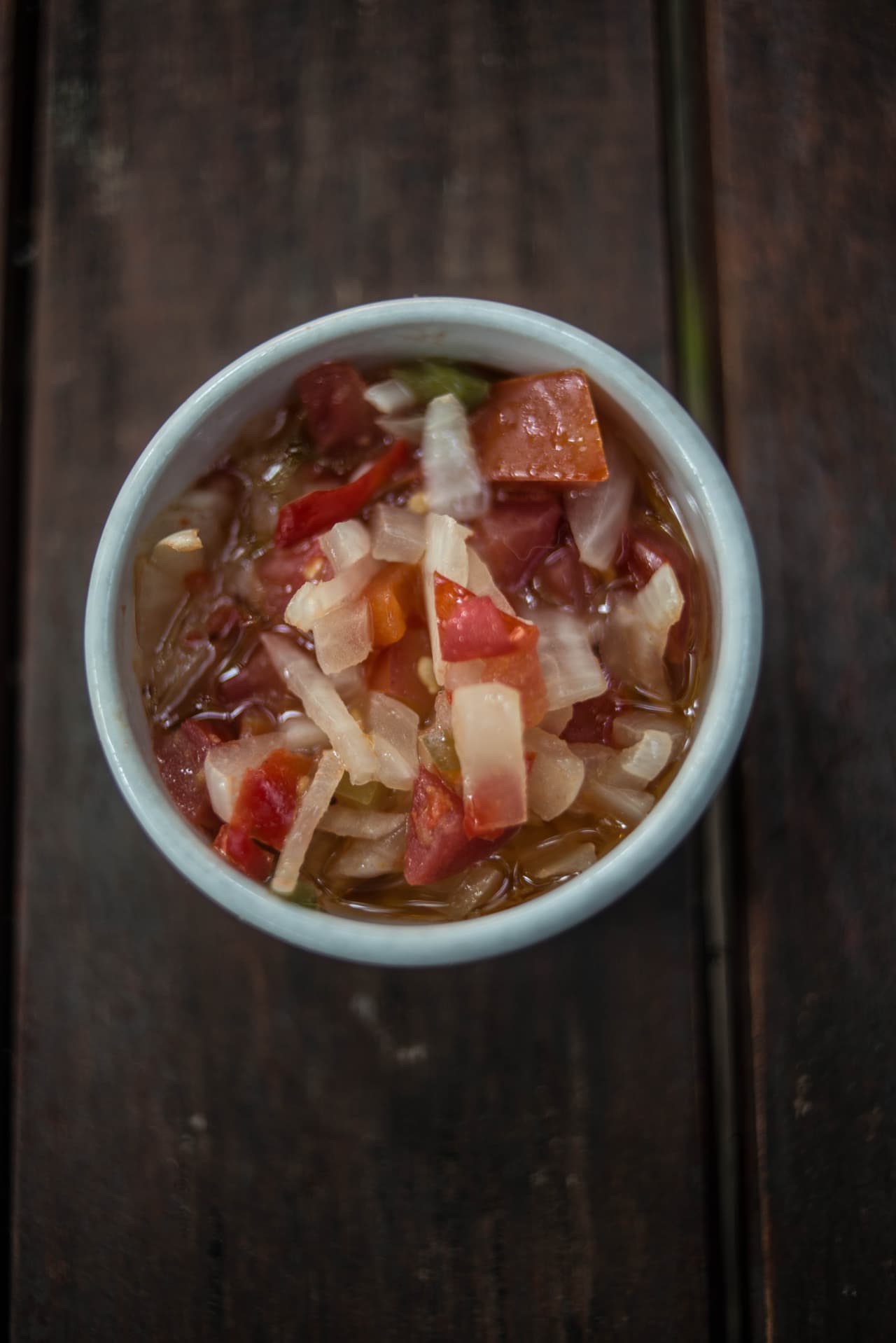 La salsa criolla se obtiene mezclando tomate, cebolla, aceite, ají y vinagre de vino.