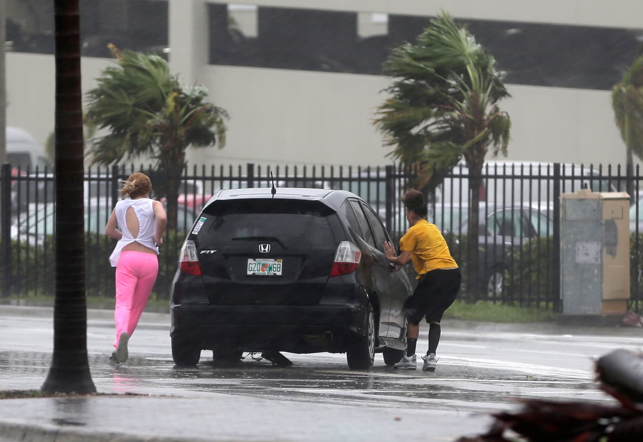 Dos personas intentan regresar a su automóvil en medio de los vientos del huracán Irma en Hialeah, ciudad de los alrededores de Miami. Ráfagas de viento de 82 mph fueron reportadas en Miami, según la agencia AP.