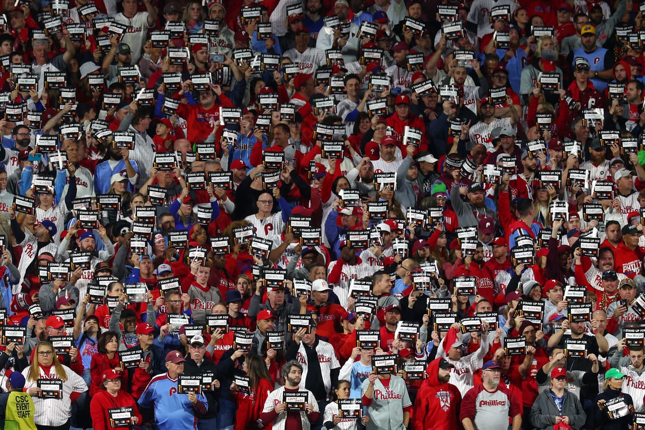 Miles de aficionados sostienen carteles de "
<b>Stand Up to Cancer</b>" durante el Juego 4 de la Serie Mundial entre los Astros de Houston y los Phillies de Filadelfia en el Citizens Bank Park el 2 de noviembre de 2022.