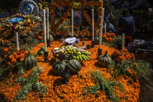 Una típica ofrenda con flor de cempasúchil, calabazas y otras frutas, así como alimentos en recuerdo a la comida favorita del difunto.