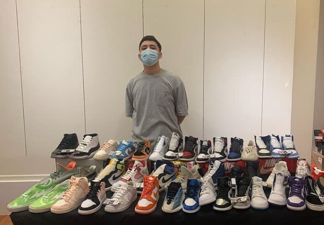 Efraín González posa con los tenis que vendía en su tienda en El Monte, California.