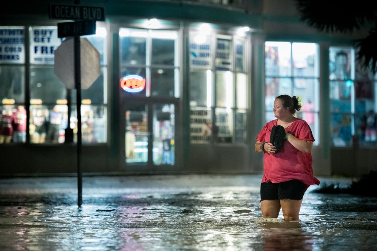Una mujer camina a través de las inundaciones en Ocean Boulevard el 3 de agosto de 2020 en Myrtle Beach, Carolina del Sur, causada por la llegada del huracán Isaías.