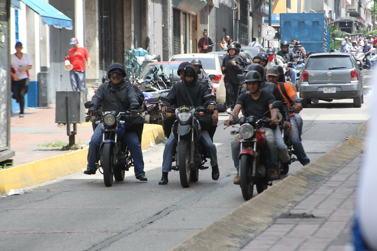 Los colectivos se desplazan en grupos motorizados, algunos de ellos con sus rostros cubiertos. Los habitantes de las zonas populares de Caracas los reconocen apenas los ven llegar a violentar manifestaciones opositoras. En la foto, un 'colectivo' llega a frente del Ministerio Público en el centro de Caracas el 31 de marzo de 2017.
<br>