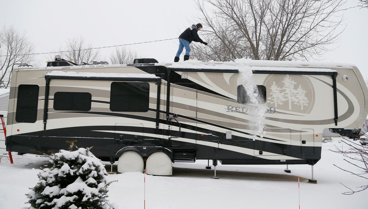 Stan DeSerano limpia la nieve de su auto en Coachman Drive.