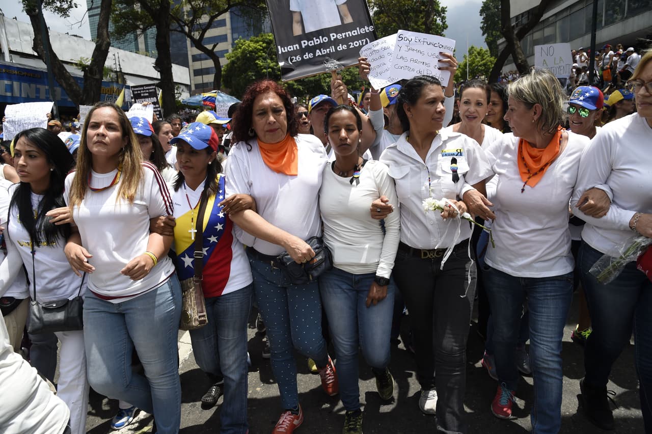 Encabezadas por diputadas como
<a href="http://especiales.univision.com/perfiles-nueva-venezuela/tamara-adrian/">Tamara Adrián</a> y
<a href="http://especiales.univision.com/perfiles-nueva-venezuela/marialbert-barrios/">Marialbert Barrios</a>, miles de mujeres caminaron rumbo al Ministerio de Interior y Justicia, en el centro de Caracas, para rechazar que los cuerpos de seguridad dispersen las protestas contra el gobierno con gases lacrimógenos, perdigones y chorros de agua a presión. Al fondo, el nombre de uno de los jóvenes fallecidos: Juan Pablo Pernalete.