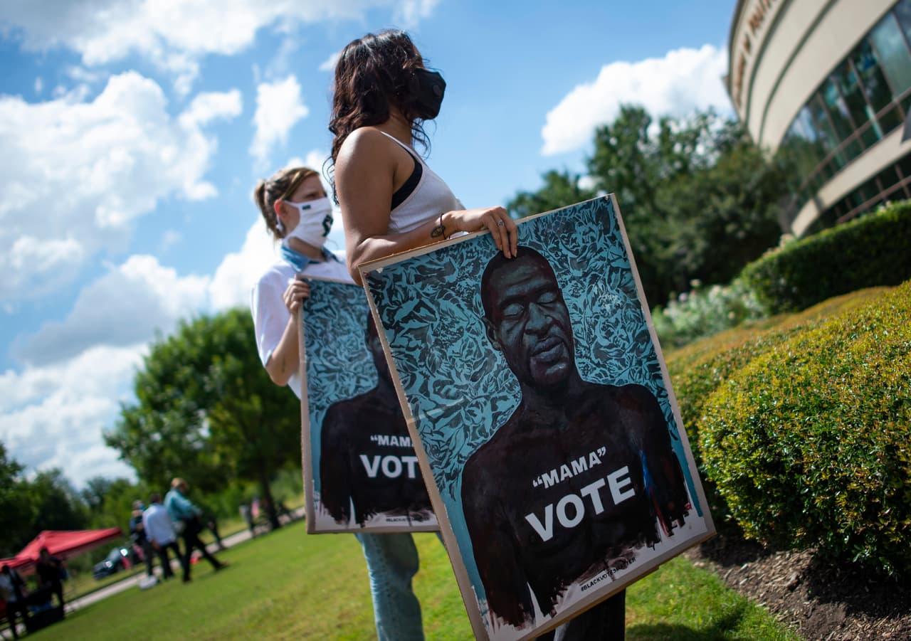 Otros asistentes al funeral con carteles llamando a votar en las elecciones presidenciales del próximo noviembre. 