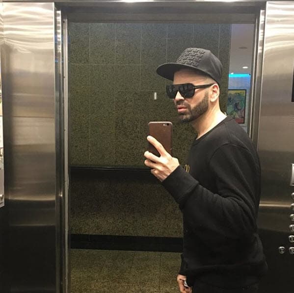 Gorra, suéter negro y lentes oscuros, atuendo con el que luce muy relajado.