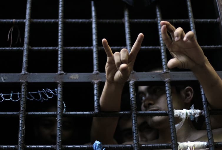A man flashes his gang’s hand sign from inside a jail cell at a police station in San Salvador, El Salvador.