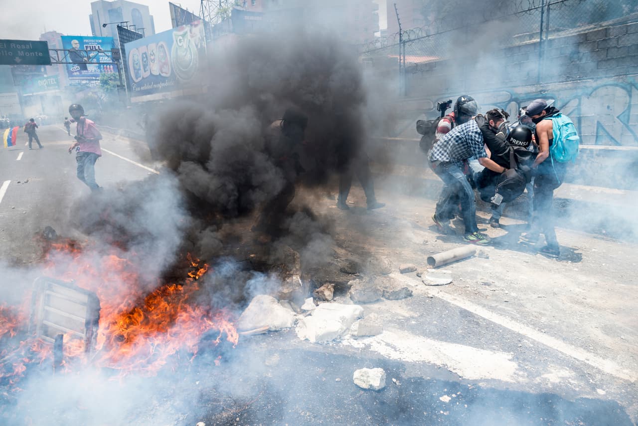 Un grupo de fotoperiodistas auxilian al reportero Román Camacho, quien sufrió una fractura en la pierna izquierda luego de que un soldado de la Guardia Nacional le disparara una bomba lacrimógena. 10 de abril de 2017.