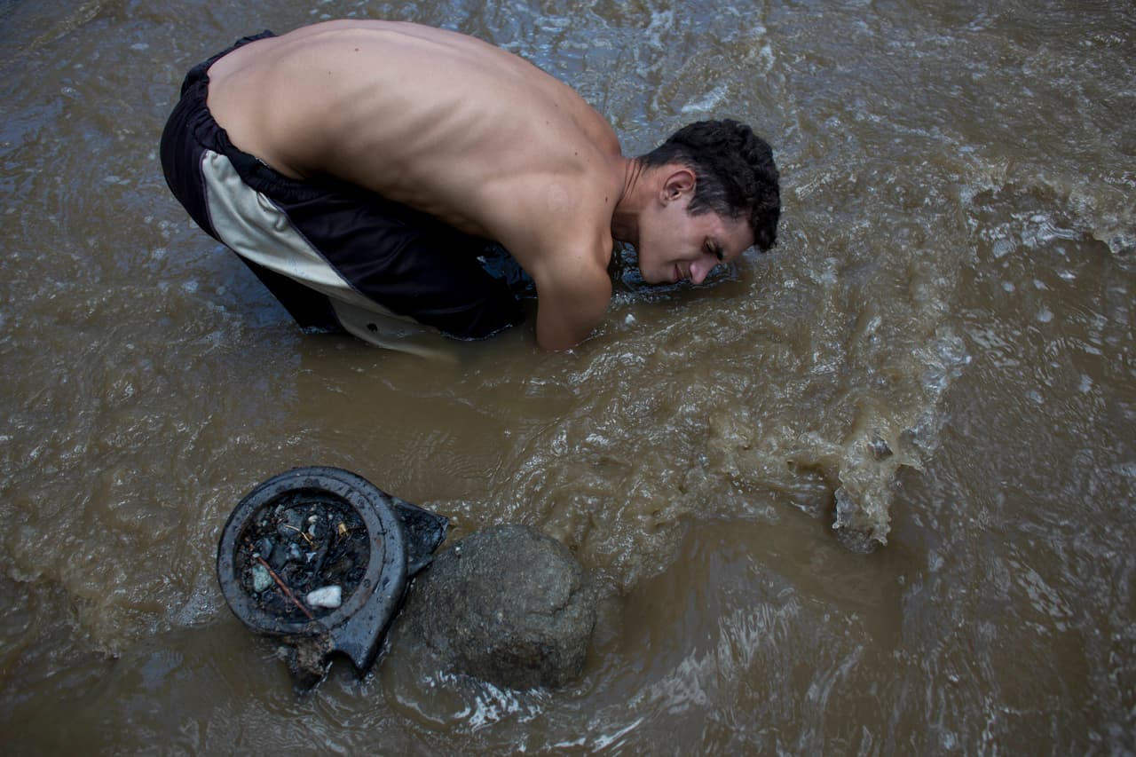 El venezolano David García escarba el fondo del Guaire, un río contaminado que atraviesa Caracas, capital de Venezuela. García intenta encontrar oro o cualquier otra cosa de valor en las aguas residuales, su única manera de obtener los recursos para mantener a su familia en un país con la economía destruida. La imagen fue tomada en mayo de 2017.