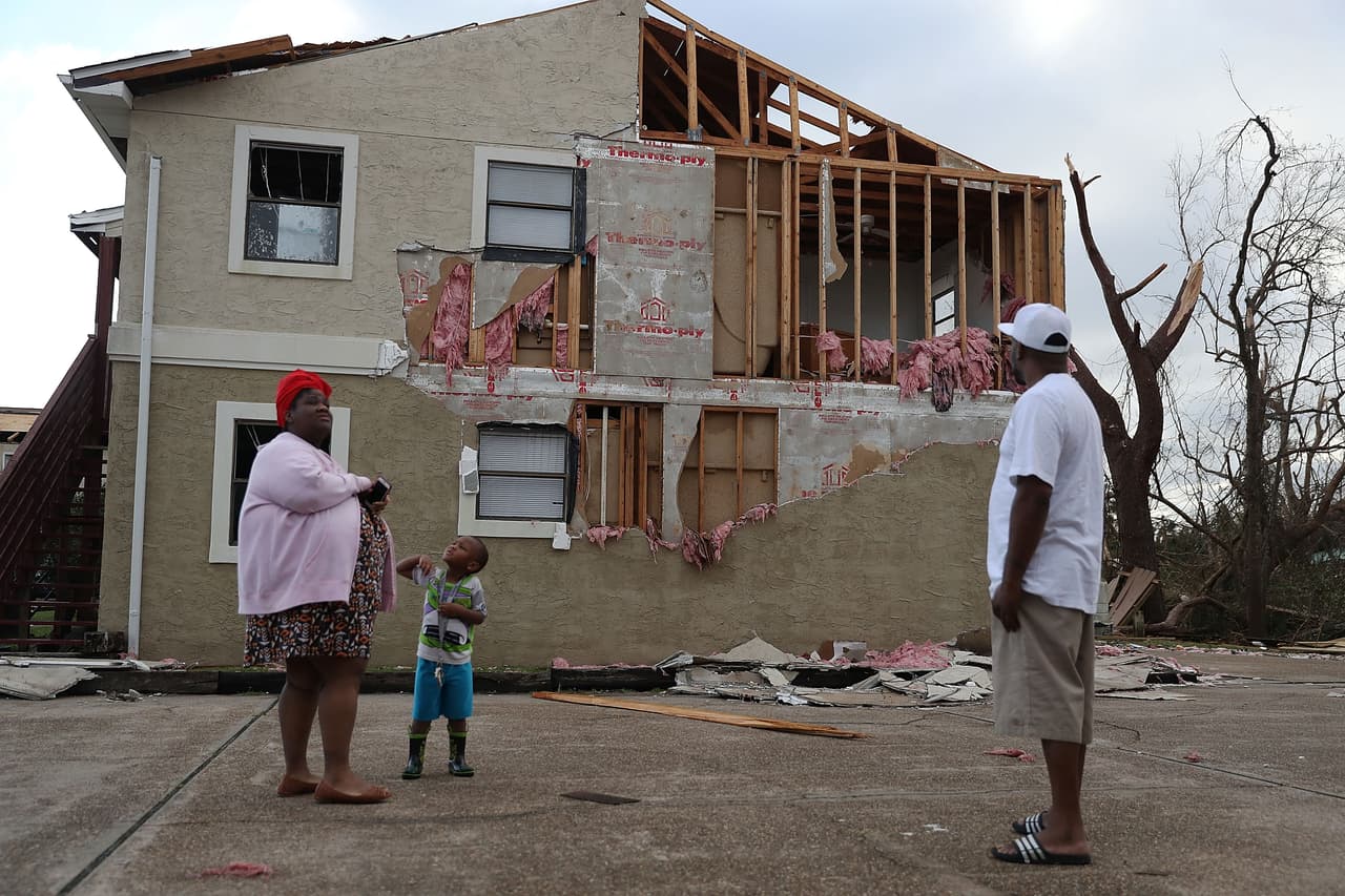 Comeasha Stanley, Ramari Stanley y Terrell Atkinson, residentes de Panama City frente a un complejo de apartamentos destrozado.