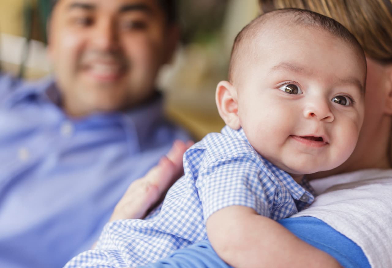 Happy Attractive Mixed Race Couple Burping Their Smiling Son.