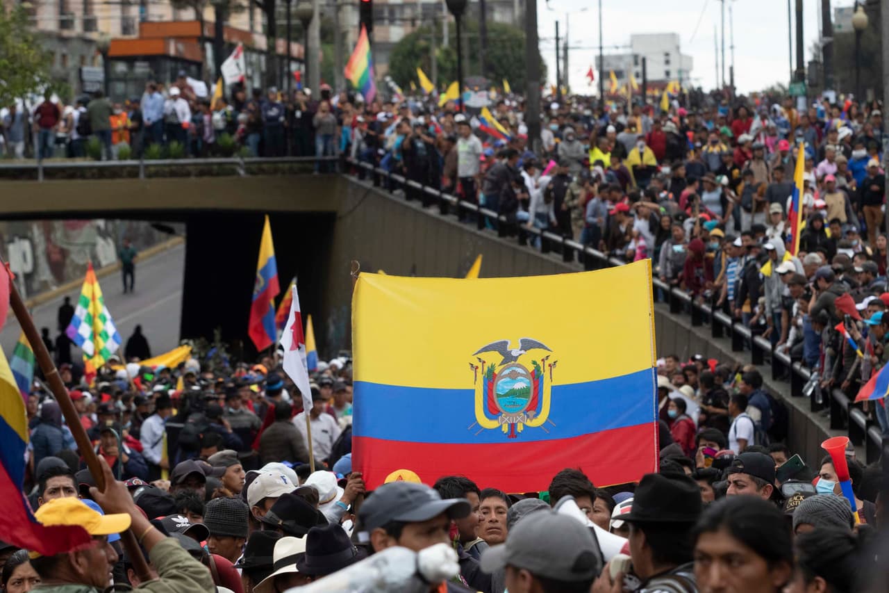 Manifestantes enarbolan banderas ecuatorianas mientras marchan cerca del Palacio Presidencial de Carondelet.