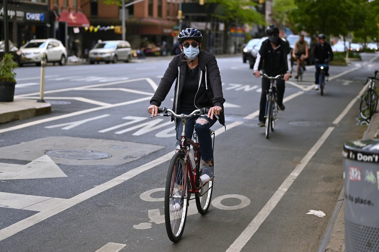 Personas con mascarillas protectoras van en bicicleta por un carril del barrio de Chelsea en Manhattan durante la pandemia de coronavirus del 24 de mayo de 2020 en la ciudad de Nueva York.