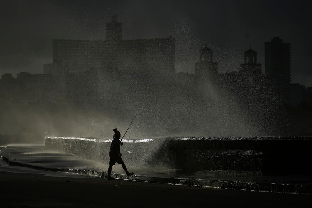 Una persona pesca en el muelle mientras las olas rompen durante un apagón en La Habana.