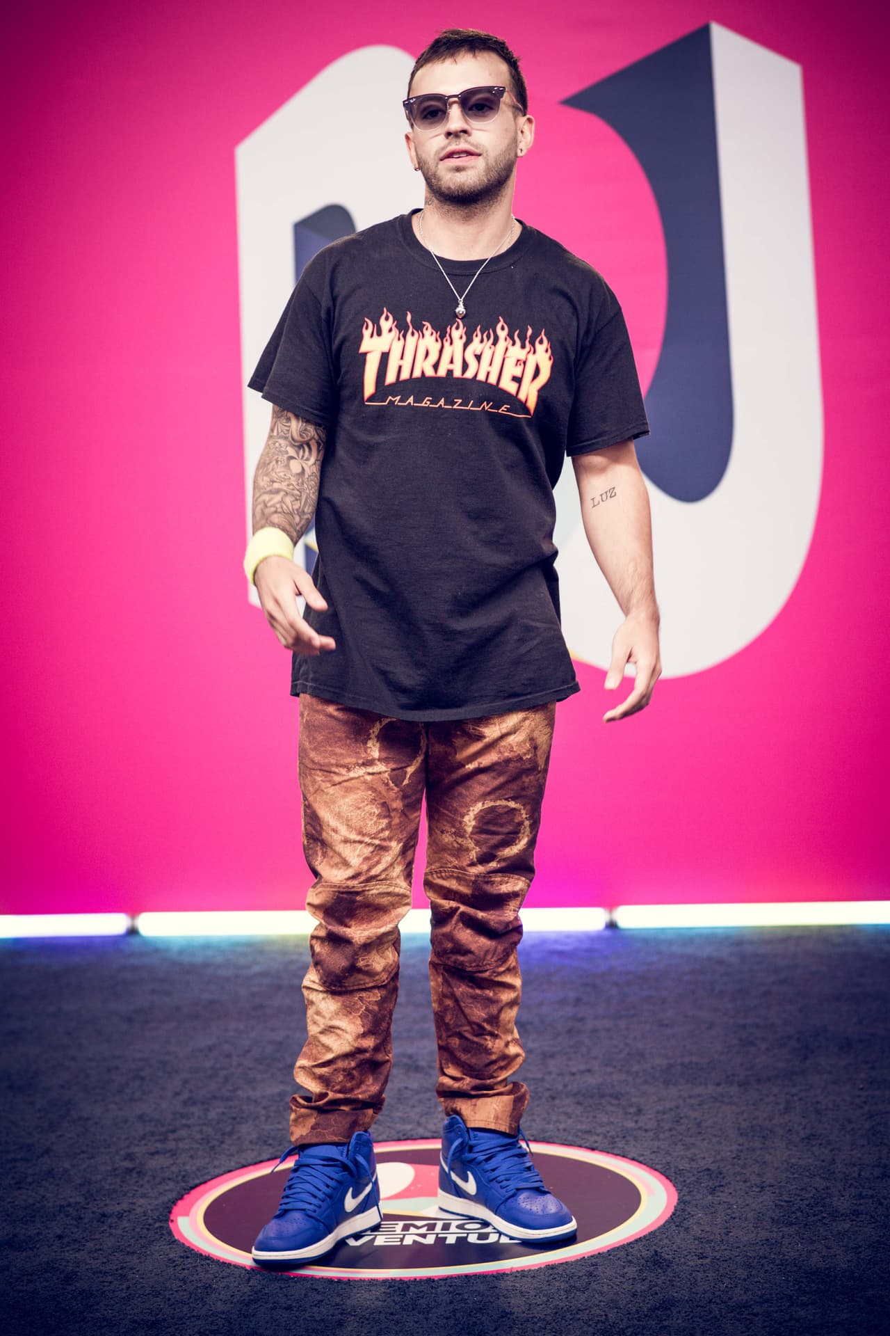 El colombiano Feid utilizó unos sneakers Nike con pantalón café deslavado y una playera negra. El complemento a su look fueron una muñequera amarilla y unos lentes oscuros.
<br>