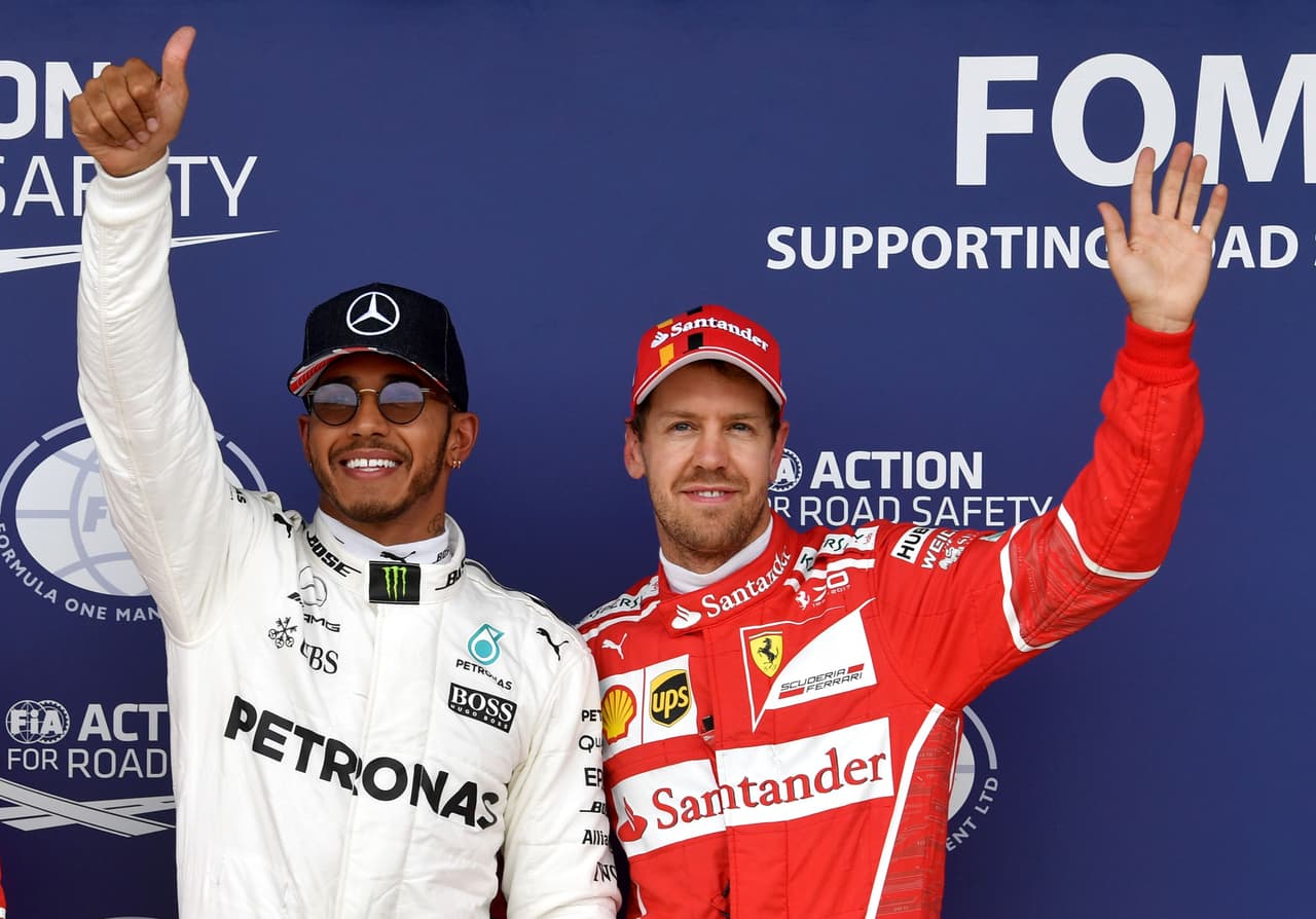 Mercedes' British driver Lewis Hamilton (L) celebrates after winning the pole position next to third placed Ferrari's German driver Sebastian Vettel during the qualifying session at the Silverstone motor racing circuit in Silverstone, central England on July 15, 2017 ahead of the British Formula One Grand Prix. / AFP PHOTO / Andrej ISAKOVIC (Photo credit should read ANDREJ ISAKOVIC/AFP/Getty Images)