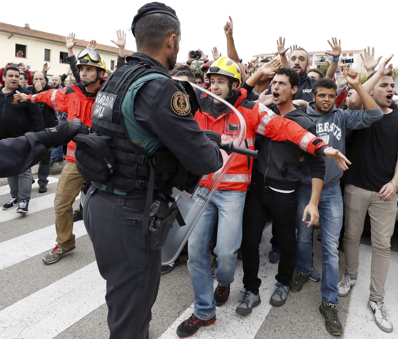 Un policía intenta hacer frenta aun grupo de manifestantes que protestan en el centro de votación de Sant Julià de Ramis (Girona).